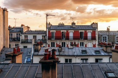 Classic Paris rooftops with chimneys and mansard windows at sunset.