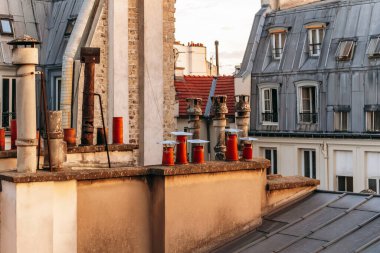 Classic Paris rooftops with chimneys and mansard windows at sunset.