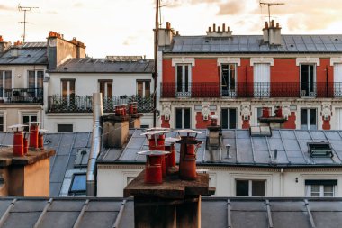 Classic Paris rooftops with chimneys and mansard windows at sunset.