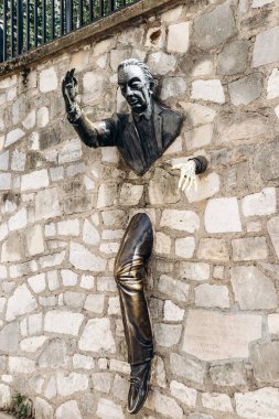 Paris, Fransa - 11 Eylül 2025 Montmartre 'deki Muraille heykeli taş bir duvarın içinden geçen bronz bir adamı gösteriyor.