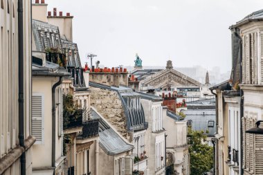 Paris, France - September 11, 2025: Rooftop view from Montmartre near Abbesses with classic Parisian facades, shutters, and a distant historic pediment visible above the rooftops.