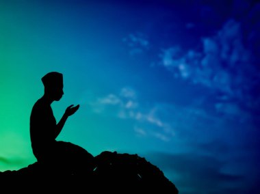 Silüet konsepti: Müslüman adam tepede Allah 'a dua ediyor. Güzel, doğal bir günbatımı manzarası var. İnsanlara odaklan.