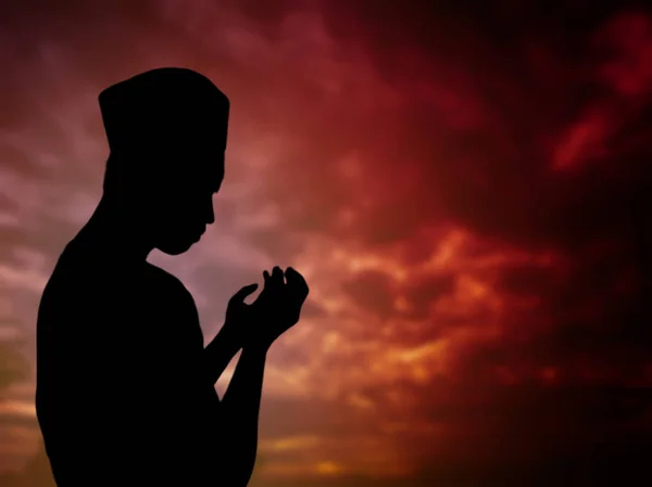 Silüet konsepti: Müslüman adam tepede Allah 'a dua ediyor. Güzel, doğal bir günbatımı manzarası var. İnsanlara odaklan.