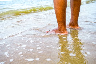 Düşük açı, Asyalı adamın ayakları denizde. Yumuşak deniz suyu ve deniz kumuyla. Ayaklara odaklan, gürültülü, teşhir, benzer şeyler.