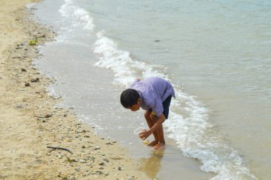 Lamongan-Endonezya, 13 Aralık 2024: Pantai Putri Klayar 'da tatilde olan çocuklar yüzüyor, kumsalda kumla oynuyor. Çocuklara odaklan, Gürültülü, teşhir, benzerleri
