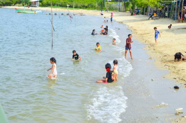 Lamongan-Endonezya, 13 Aralık 2024: Pantai Putri Klayar 'da tatilde olan çocuklar yüzüyor, kumsalda kumla oynuyor. Çocuklara odaklan, Gürültülü, teşhir, benzerleri