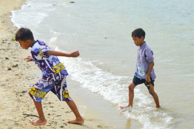 Lamongan-Endonezya, 13 Aralık 2024: Pantai Putri Klayar 'da tatilde olan çocuklar yüzüyor, kumsalda kumla oynuyor. Çocuklara odaklan, Gürültülü, teşhir, benzerleri
