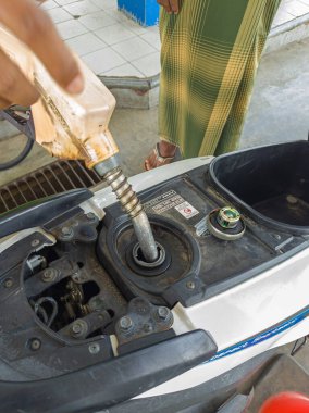 Gresik-Endonezya, 13 Aralık 2024: SPBU Pertamina 'da motorsiklete pertalit benzin dolduran benzin istasyonu görevlisi. Benzin pompasına odaklan. Gürültü, maruz kalma, benzer şeyler.