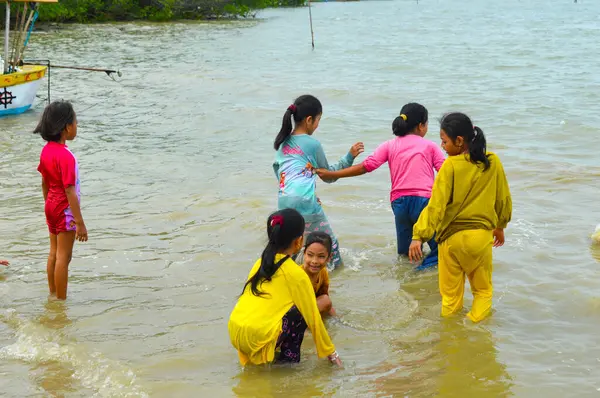 Lamongan-Endonezya, 13 Aralık 2024: Pantai Putri Klayar 'da tatilde olan çocuklar yüzüyor, kumsalda kumla oynuyor. Çocuklara odaklan, Gürültülü, teşhir, benzerleri