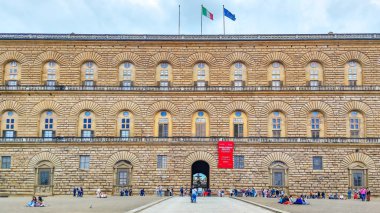 Floransa, İtalya - 18 Mayıs 2023: Pitti Sarayı 'nın çatısında İtalya ve Avrupa Birliği bayrakları. Ön planda, Palazzo Pitti 'nin önündeki insanlar...