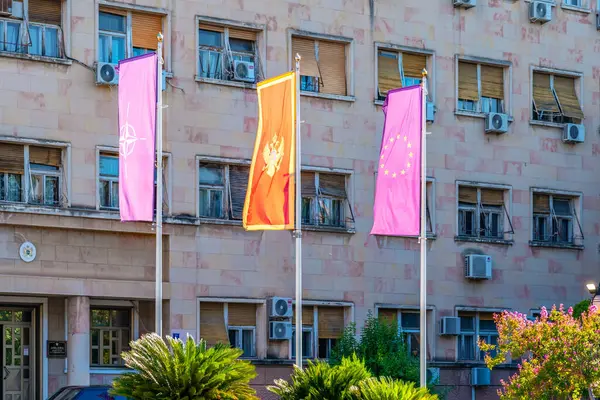 Podgorica, Karadağ - 08 Ağustos 2023: Karadağ, AB ve NATO bayrakları evlerin arka planında bir bayrak direğinde dalgalanıyor