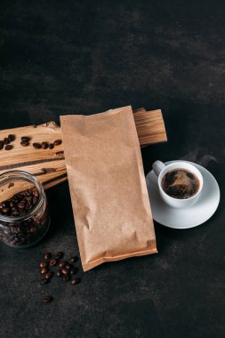 Beyaz bardakta espresso americano kahvesi, kahve çekirdekleri, ahşap arka plan, bir kavanoz kahve çekirdeği.