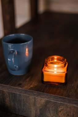 Masada yanan bir mumun bardakla dikey görüntüsü.