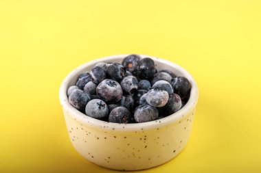 Mavi arka planda cam bir kasede taze yaban mersini.