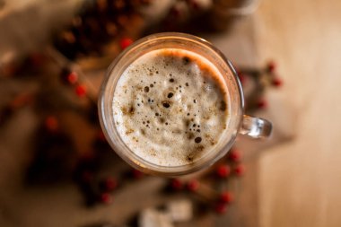 Masada bir fincan kahve var. Arka planda Noel süslemeleri var. Üst tarafta düz yatak var.