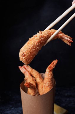 Çubuklu bir tabakta lezzetli kızarmış karidesler. koyu arkaplan