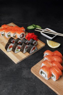 Somon, somon, avokado, somon, somon, ton balığı, suşi ve wasabi ile siyah arkaplanda. Japon yemeği..