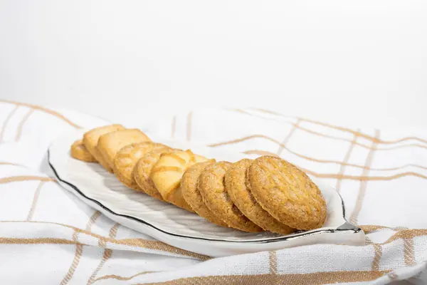 Danish cookies on a white ceramic tray on a towel on a white background, breakfast, pastries, delicious shortbread cookies, white background, catalog photo of food
