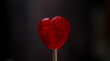 Kırmızı kalp şeklinde lolipop koyu bir arka planda
