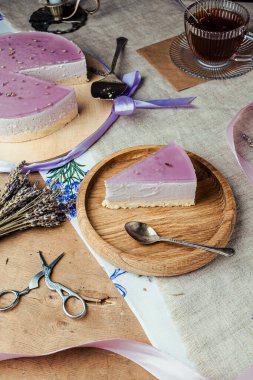 Kısa hamurlu lavantalı cheesecake, kırsal tarzda mor jöle, cam bardakta çay, ahşap zemin, lavanta tatlısı, yassı, pastayla hayat.