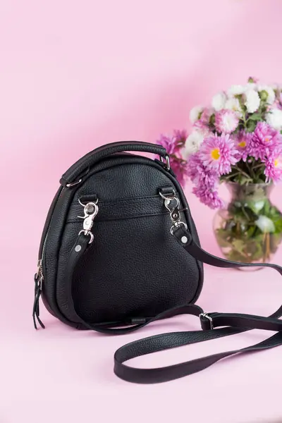 Çiçekli moda çantası ve pembe arka planda güneş gözlüğü.