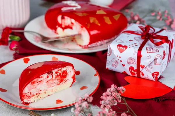 Beyaz bir tabakta altın desenli kırmızı bir kremalı pasta, kırmızı ve pembe karanfiller, güller, vazoda çingene, Sevgililer Günü pastası, doğum günü, aydınlık arka plan, yemek fotoğrafı.