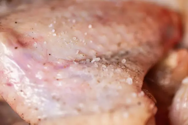 Kaba tuz ve karabiber serpilmiş bir kasede tavuk kanatları. Kanatlar taze görünüyor ve terbiye edilmeye hazır. Baharat. Yemek hazırlığı. Kaliteli fotoğraf