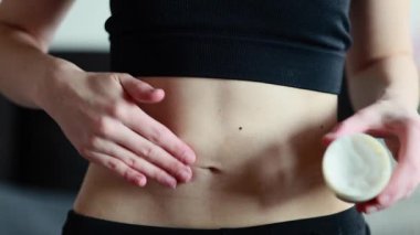 Bir kadın doğum yaptıktan sonra ince karnına gerilme önleyici krem sürer. Cilt bakımı. Nemlendirici vücut kremi kullanıyorum. Gerilme önleyici krem. Hamilelikten sonra cilt bakımı.