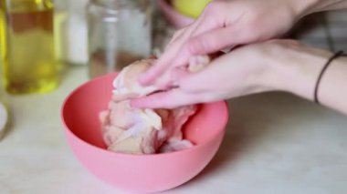 Tavuk kanadı terbiye eden kadın. Tavuk kanatlarını tuz ve karabiberle marine etmek. Mutfak masasının yüzeyine baharatla et sürterek..
