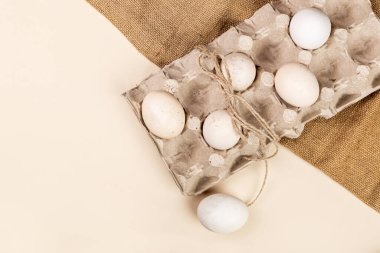 Yumurta standındaki doğal yumurtalar, hafif bir arka planda çuval bezi, Paskalya için hazırlık, Paskalya için yumurta boyama, çiftlik konsepti, kırsal, hafif arka planda yumurta.