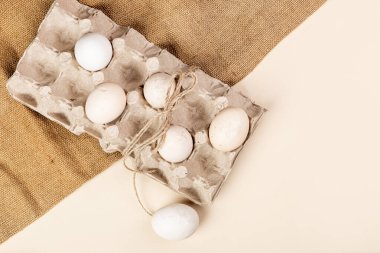 Yumurta standındaki doğal yumurtalar, hafif bir arka planda çuval bezi, Paskalya için hazırlık, Paskalya için yumurta boyama, çiftlik konsepti, kırsal, hafif arka planda yumurta.