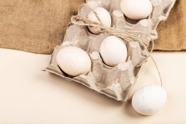 Yumurta standındaki doğal yumurtalar, hafif bir arka planda çuval bezi, Paskalya için hazırlık, Paskalya için yumurta boyama, çiftlik konsepti, kırsal, hafif arka planda yumurta.