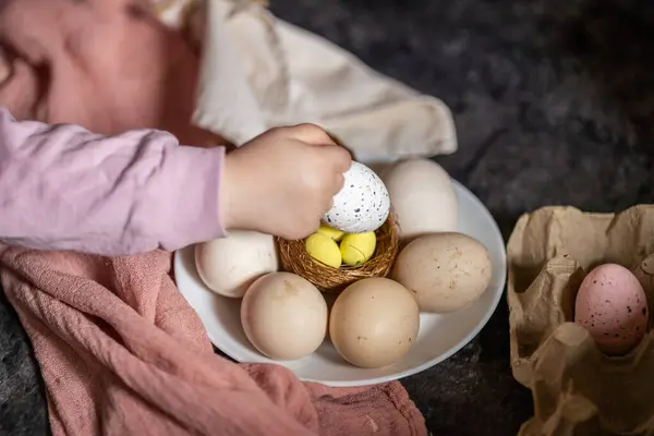 Çocuk Paskalya için yumurta boyuyor, çocukla Paskalya hazırlığı yapıyor, süs yuvasında sarı bıldırcın ve tavuk yumurtası boyuyor, aile tatili, Paskalya için hazırlanan küçük çocuk.