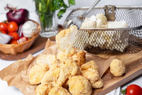 Karnabahar kızartması bir çatalla dilimlenmiş, yağsız bir tabak, hamurda karnabahar. Sağlıklı fast food. Düşük kalorili yemek kızartması. Lahana, domates. Kızartma makinesi. Yüksek kalite fotoğraf.