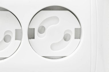 Çocuk geçirmez soket. Prizi prize tak. Evde bir çocuğu nasıl koruyacağını. Çocuk korumalı beyaz bir duvarda beyaz bir soket. Evde çocuk güvenliği.