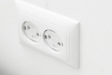 Çocuk geçirmez soket. Prizi prize tak. Evde bir çocuğu nasıl koruyacağını. Çocuk korumalı beyaz bir duvarda beyaz bir soket. Evde çocuk güvenliği.