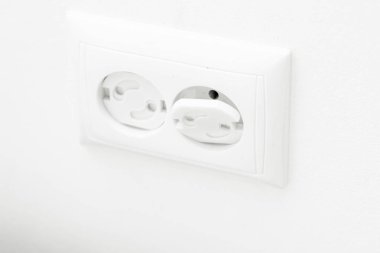 Çocuk geçirmez soket. Prizi prize tak. Evde bir çocuğu nasıl koruyacağını. Çocuk korumalı beyaz bir duvarda beyaz bir soket. Evde çocuk güvenliği.