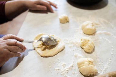 Büyükannem pastaları çiğ hamurun üzerine koyuyor. Etli turtalar, soğan, yumurta. Ev yapımı turtalar. Büyükannenin elleri..
