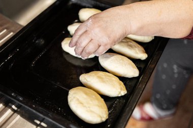 Büyükannenin elleri kalıplı turtaları yemek tepsisine koyar. Et, kiraz ve elmalı ev yapımı turtalar..