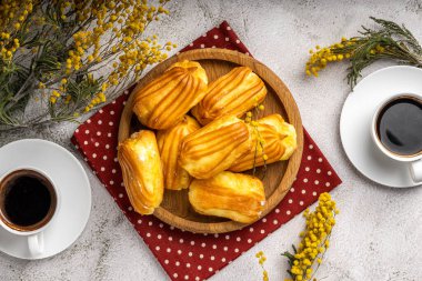 Kremalı Fransız ekini. Tahta tabakta kremalı profiterol. Eclairs çekici görüntüsü. Flatlay. Doğal ışıklandırma. Kremalı ev yapımı hamur işleri..