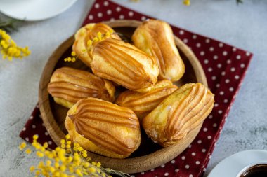 Kremalı Fransız ekini. Tahta tabakta kremalı profiterol. Eclairs çekici görüntüsü. Flatlay. Doğal ışıklandırma. Kremalı ev yapımı hamur işleri..