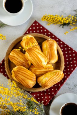 Kremalı Fransız ekini. Tahta tabakta kremalı profiterol. Eclairs çekici görüntüsü. Flatlay. Doğal ışıklandırma. Kremalı ev yapımı hamur işleri..