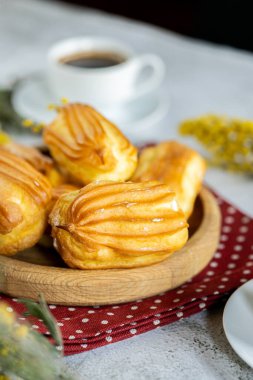 Kremalı Fransız ekini. Tahta tabakta kremalı profiterol. Eclairs çekici görüntüsü. Flatlay. Doğal ışıklandırma. Kremalı ev yapımı hamur işleri..