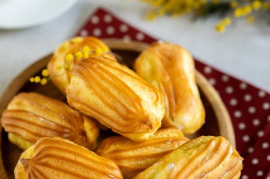 Kremalı Fransız ekini. Tahta tabakta kremalı profiterol. Eclairs çekici görüntüsü. Flatlay. Doğal ışıklandırma. Kremalı ev yapımı hamur işleri..