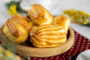 Kremalı Fransız ekini. Tahta tabakta kremalı profiterol. Eclairs çekici görüntüsü. Flatlay. Doğal ışıklandırma. Kremalı ev yapımı hamur işleri..