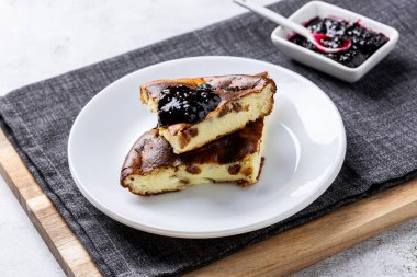 Beyaz tabakta çilek reçeli süzme peynir güveci. Süzme peynir ve kuru üzümlü ev yapımı güveç..