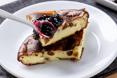 Beyaz tabakta çilek reçeli süzme peynir güveci. Süzme peynir ve kuru üzümlü ev yapımı güveç..