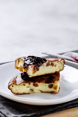 Beyaz tabakta çilek reçeli süzme peynir güveci. Süzme peynir ve kuru üzümlü ev yapımı güveç..