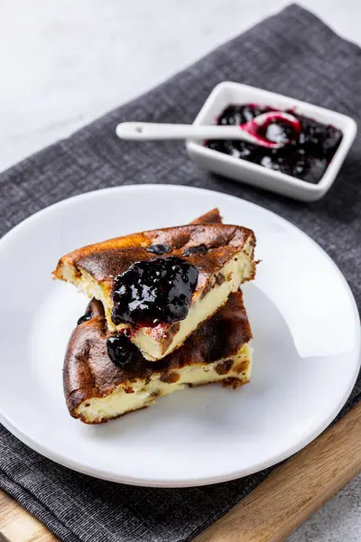 Beyaz tabakta çilek reçeli süzme peynir güveci. Süzme peynir ve kuru üzümlü ev yapımı güveç..