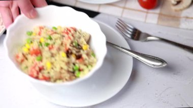 Kuskus, buğday tanelerinden (irmik ya da darı) yapılan bir yemektir. Mantarlı kuskus, mısır, bezelye, şifalı ot, domates. Yan görüş. Flatlay. Hafif arka planda kuskus. Beyaz tabakta kuskus.